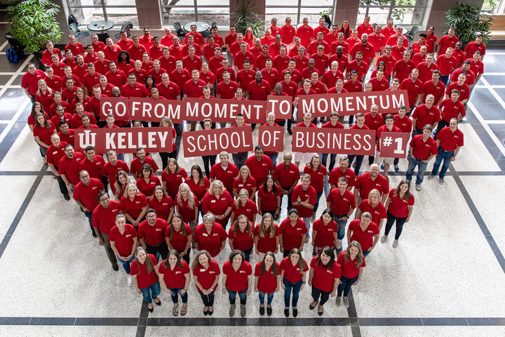 Kelley School of Business students pose with a sign reading "From moment to momentum"